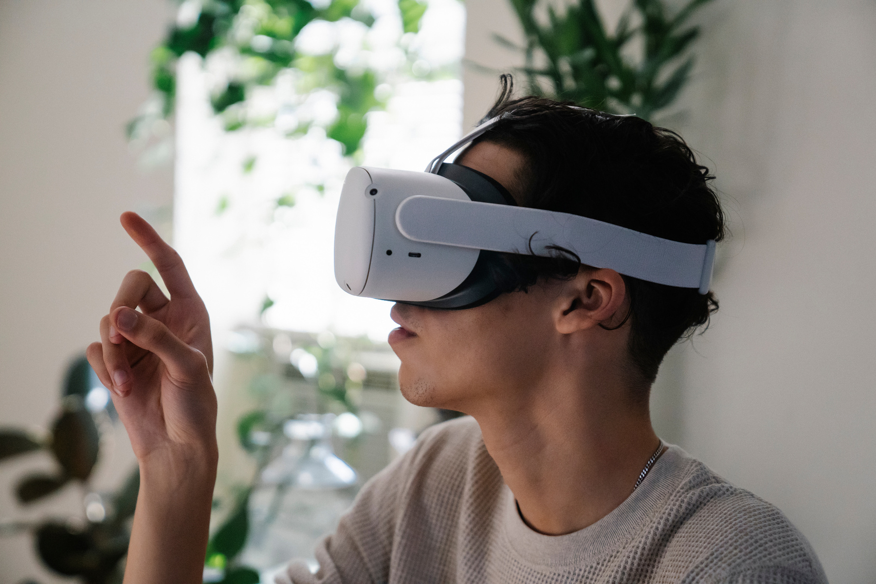 Young male millennial in VR goggles looking at finger
